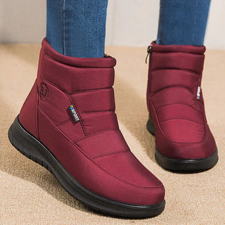 Maroon ankle boots worn with blue jeans on a beige carpet.