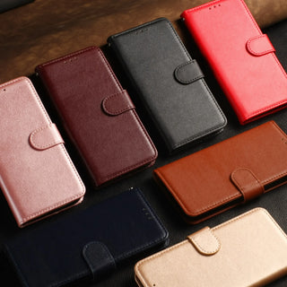 Six wallet-style phone cases arranged on a dark textured surface, showing different color options: pink, burgundy, black, red, brown, navy, and beige.